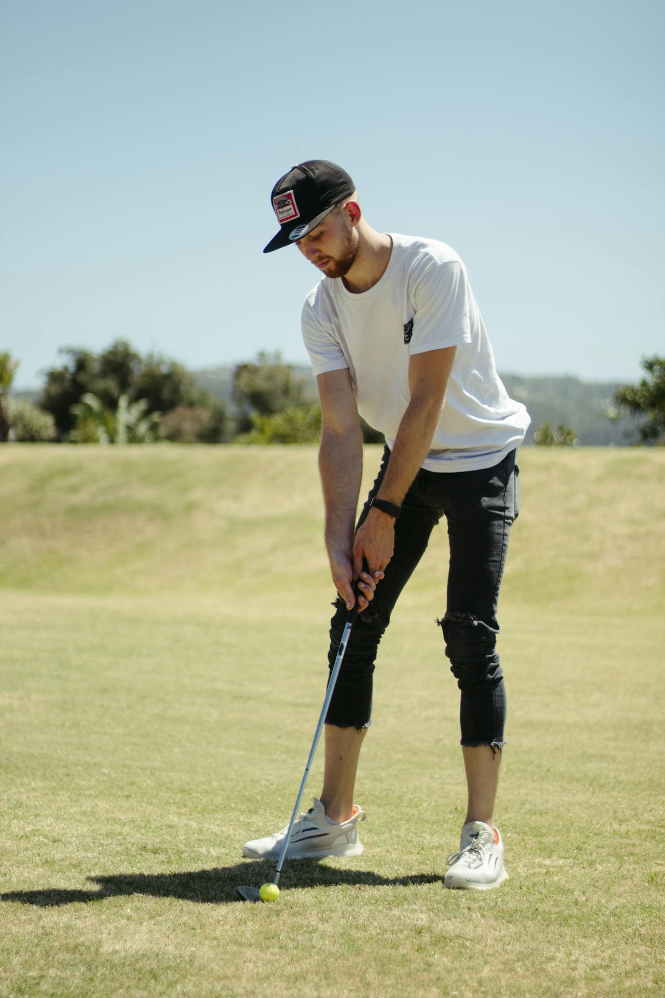 Man playing golf in field in sunny day